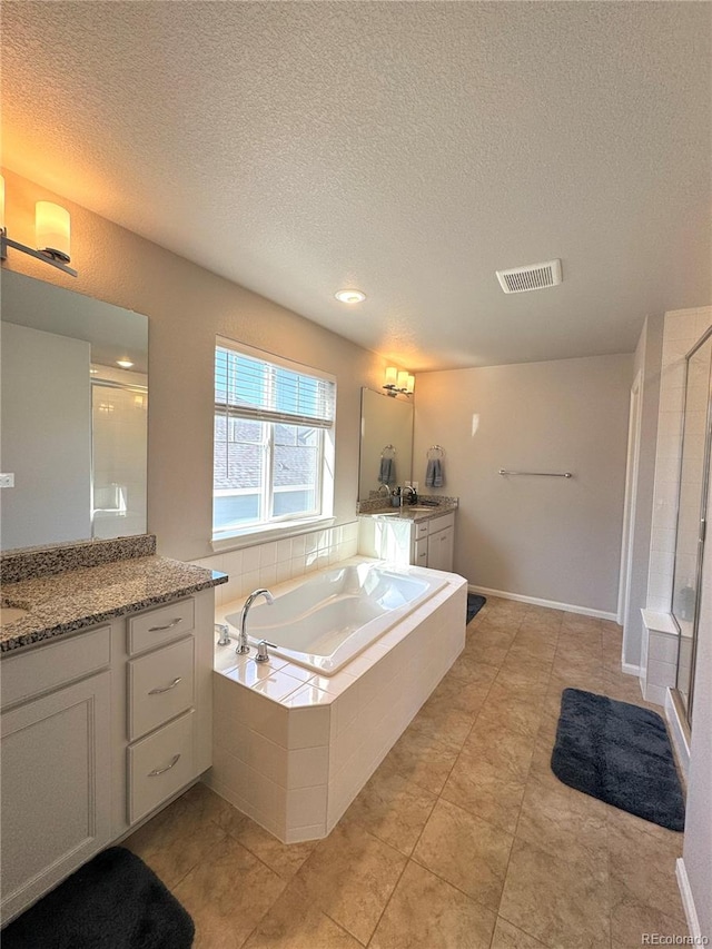 bathroom featuring shower with separate bathtub, tile patterned floors, a textured ceiling, and vanity