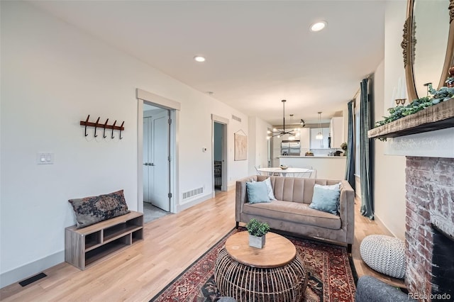 living room featuring light wood finished floors, visible vents, recessed lighting, and baseboards