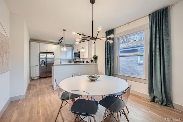 dining space featuring light wood finished floors, a chandelier, and baseboards