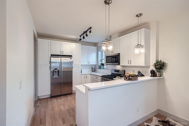 kitchen featuring light wood-type flooring, light countertops, a peninsula, stainless steel appliances, and white cabinetry