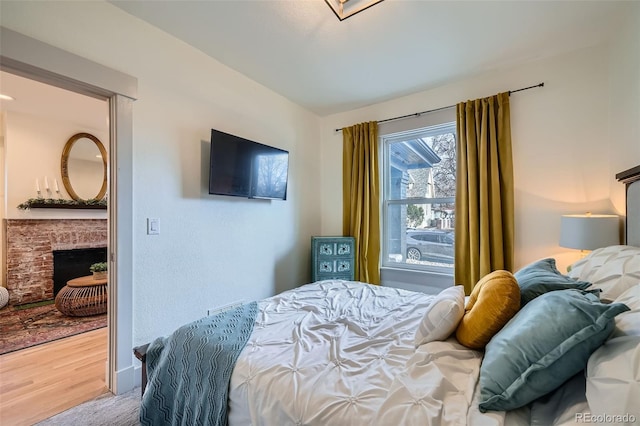 bedroom with wood finished floors and a fireplace