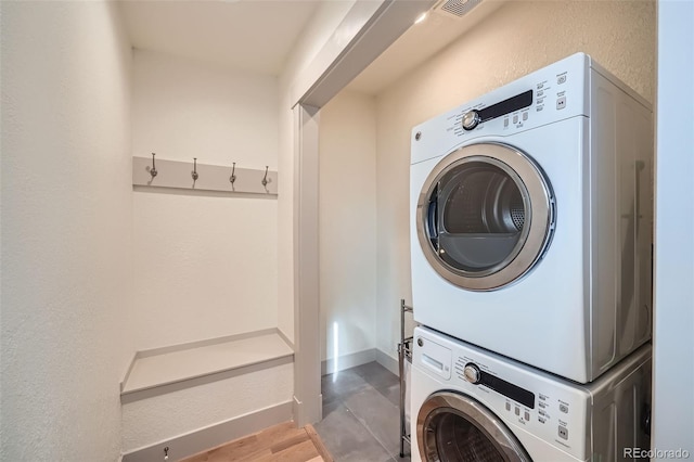 laundry room with wood finished floors, baseboards, visible vents, laundry area, and stacked washer / drying machine