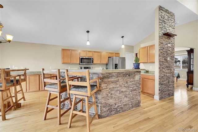 kitchen featuring light wood-type flooring, appliances with stainless steel finishes, arched walkways, and light countertops