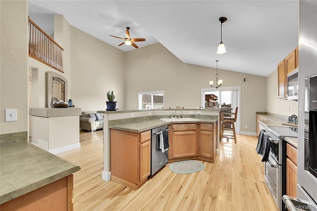 kitchen featuring open floor plan, appliances with stainless steel finishes, light wood finished floors, and a sink