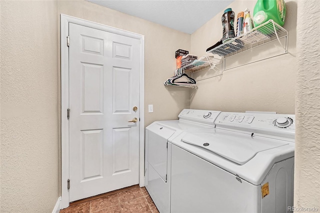 washroom with a textured wall, laundry area, and separate washer and dryer