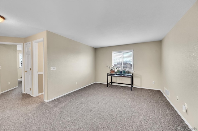 spare room with carpet floors, visible vents, and baseboards