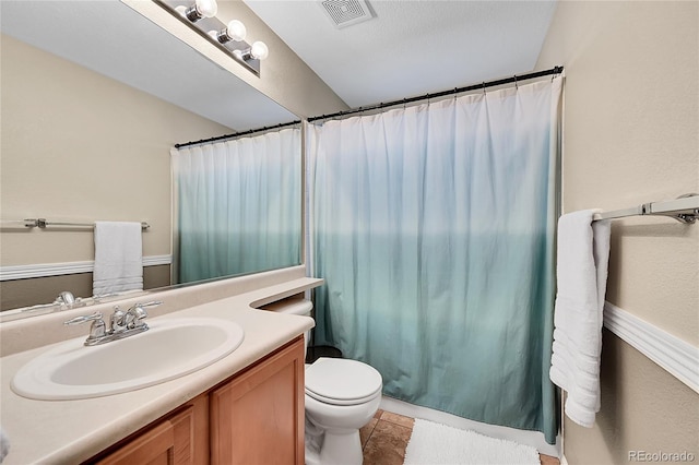 bathroom featuring visible vents, toilet, vanity, a shower with curtain, and tile patterned floors