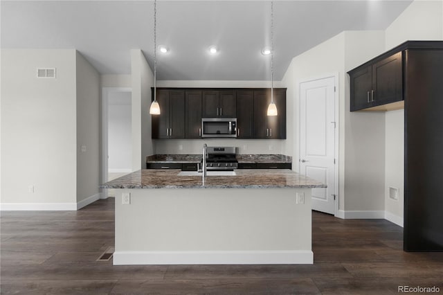 2143 Peralta Loop, Castle Rock, CO 80104 - kitchen featuring stainless steel appliances, stone countertops, an island with sink, dark brown cabinetry, and lofted ceiling