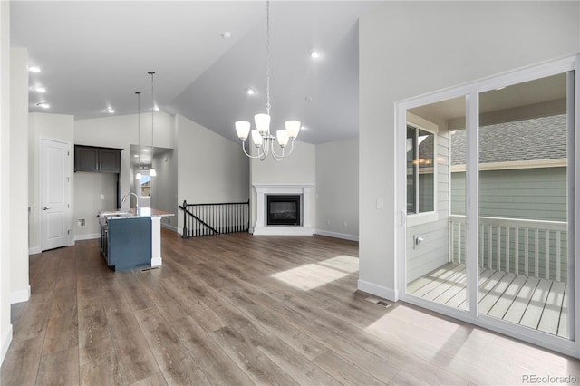 2143 Peralta Loop, Castle Rock, CO 80104 - unfurnished living room with dark wood-style flooring, a chandelier, baseboards, high vaulted ceiling, and a glass covered fireplace