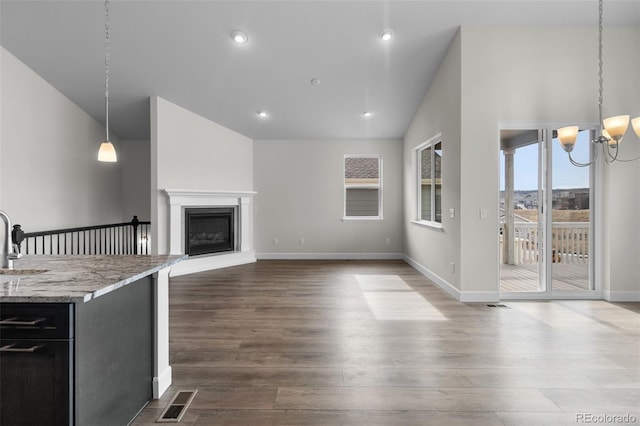 2143 Peralta Loop, Castle Rock, CO 80104 - unfurnished living room with lofted ceiling, a chandelier, dark wood-type flooring, a sink, and a glass covered fireplace