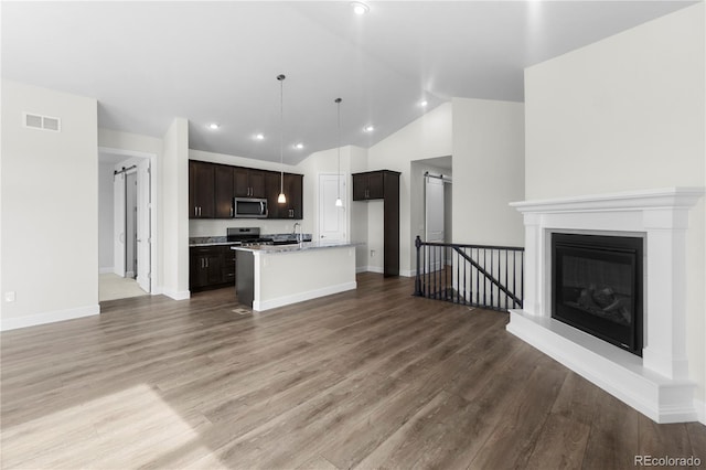 2143 Peralta Loop, Castle Rock, CO 80104 - kitchen with appliances with stainless steel finishes, open floor plan, vaulted ceiling, wood finished floors, and dark brown cabinets