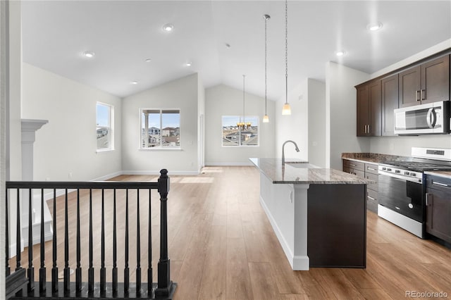 2143 Peralta Loop, Castle Rock, CO 80104 - kitchen with stainless steel gas range oven, light stone countertops, lofted ceiling, dark brown cabinets, and an island with sink