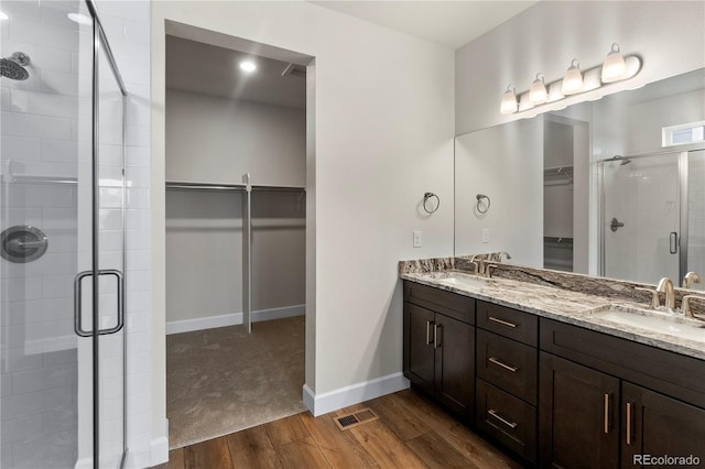 2143 Peralta Loop, Castle Rock, CO 80104 - full bathroom featuring a spacious closet, wood finished floors, a shower stall, double vanity, and baseboards