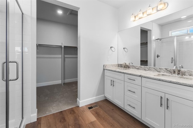 2143 Peralta Loop, Castle Rock, CO 80104 - bathroom with a walk in closet, double vanity, a stall shower, wood finished floors, and recessed lighting