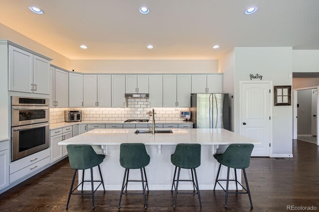 4866 Rainbow Gulch Trl, Colorado Springs, CO 80924 - kitchen with appliances with stainless steel finishes, a sink, tasteful backsplash, a kitchen island with sink, and a breakfast bar area