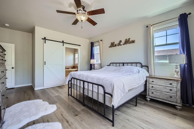 4866 Rainbow Gulch Trl, Colorado Springs, CO 80924 - bedroom with a barn door, wood finished floors, connected bathroom, a ceiling fan, and baseboards