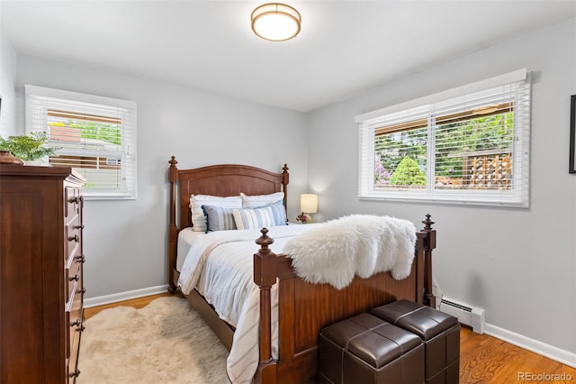 11224 W 28th Pl, Lakewood, CO 80215 - bedroom with a baseboard heating unit, light wood finished floors, and baseboards