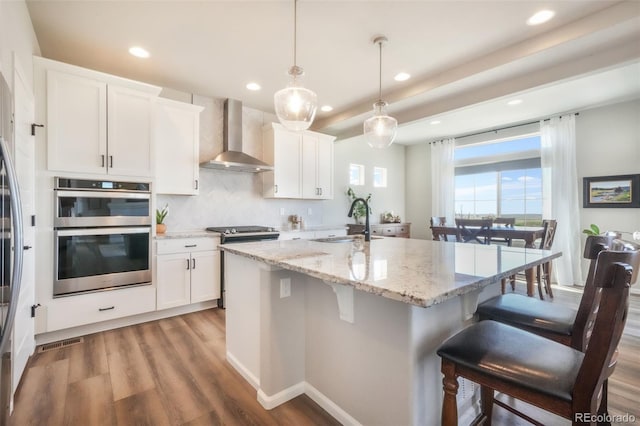 9521 Sideoats Ct, Colorado Springs, CO 80927 - kitchen with wall chimney range hood, a sink, double oven, recessed lighting, and a kitchen breakfast bar