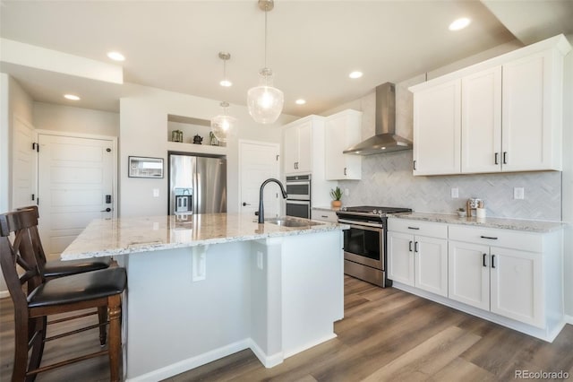 9521 Sideoats Ct, Colorado Springs, CO 80927 - kitchen featuring stainless steel appliances, wall chimney range hood, a sink, dark wood finished floors, and decorative backsplash