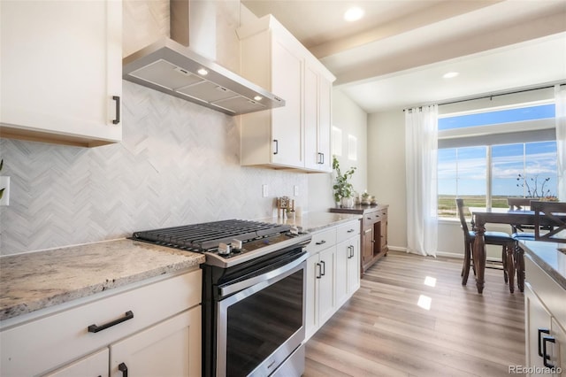 9521 Sideoats Ct, Colorado Springs, CO 80927 - kitchen featuring stainless steel gas range oven, wall chimney range hood, backsplash, white cabinets, and light stone counters