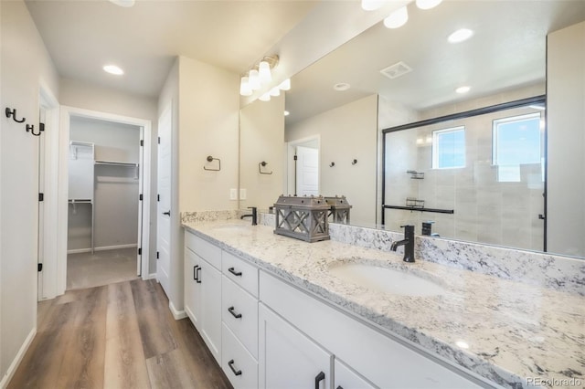 9521 Sideoats Ct, Colorado Springs, CO 80927 - bathroom with wood finished floors, a shower stall, double vanity, a spacious closet, and recessed lighting