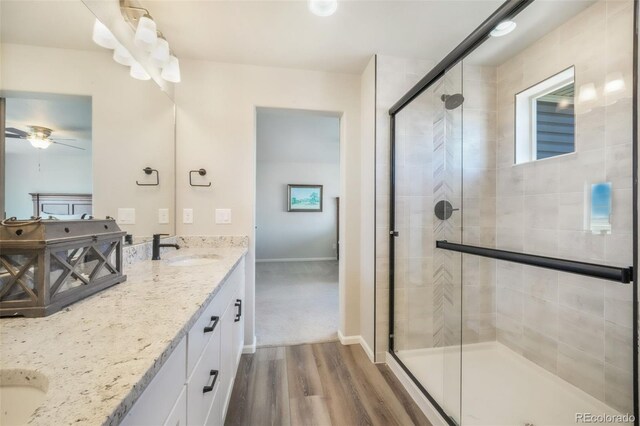 9521 Sideoats Ct, Colorado Springs, CO 80927 - full bathroom featuring double vanity, wood finished floors, a stall shower, ceiling fan, and baseboards