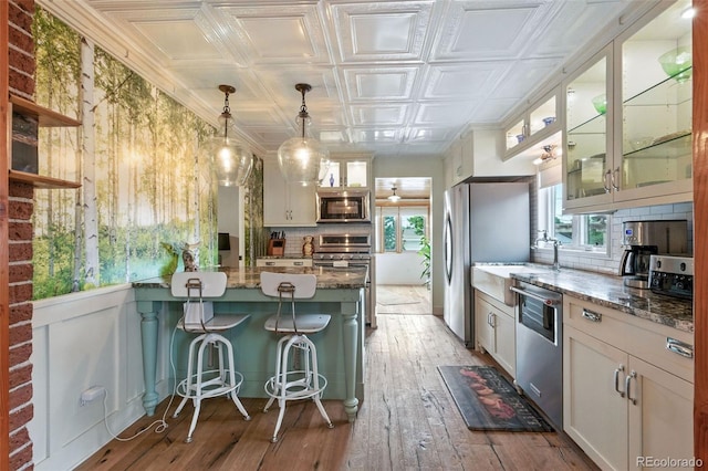 4716 Broadway, Denver, CO 80216 - kitchen with appliances with stainless steel finishes, an ornate ceiling, decorative backsplash, a peninsula, and light stone countertops