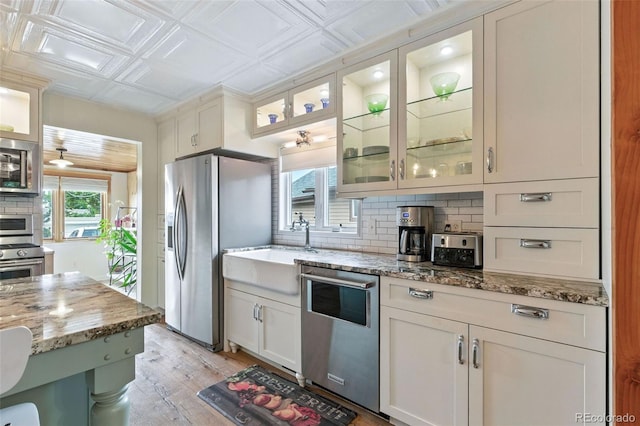 4716 Broadway, Denver, CO 80216 - kitchen featuring appliances with stainless steel finishes, backsplash, an ornate ceiling, light wood-style flooring, and light stone counters