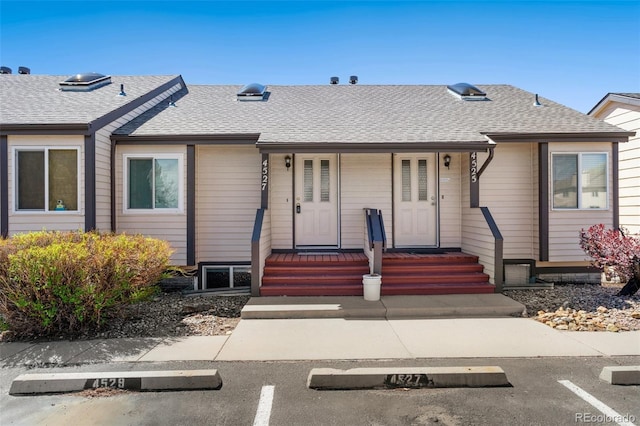view of front of house featuring uncovered parking, roof with shingles, and covered porch