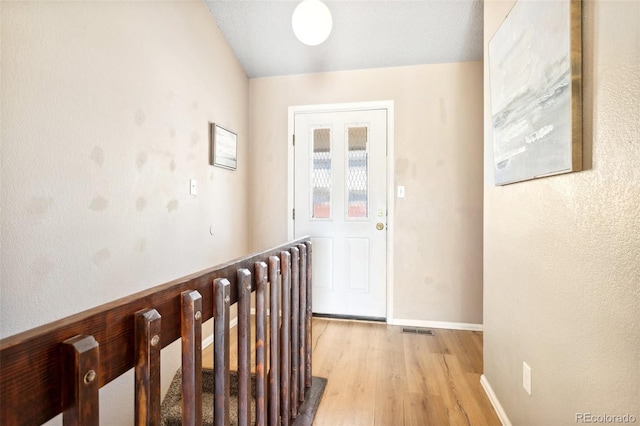hall featuring light wood-style floors, visible vents, and baseboards