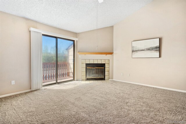 unfurnished living room with baseboards, carpet flooring, a textured ceiling, and a tiled fireplace
