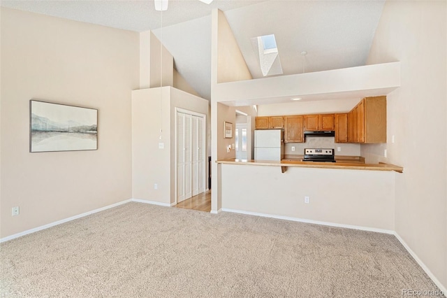 kitchen featuring light carpet, electric range, baseboards, freestanding refrigerator, and a skylight
