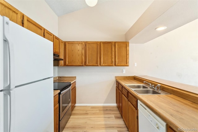 kitchen with a sink, brown cabinetry, light wood-style floors, white appliances, and under cabinet range hood