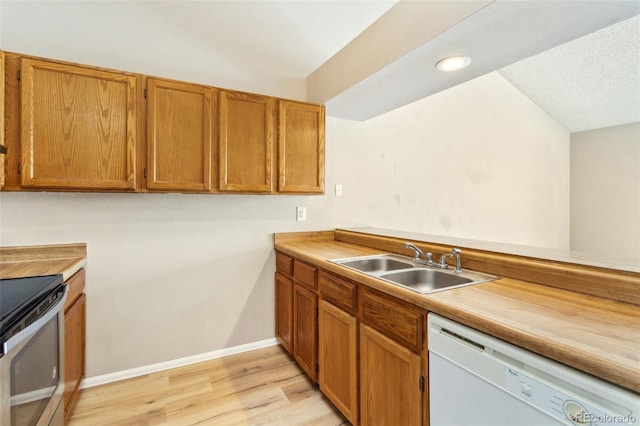 kitchen featuring white dishwasher, a sink, brown cabinets, light wood finished floors, and electric range