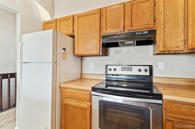 kitchen featuring freestanding refrigerator, brown cabinetry, electric stove, and under cabinet range hood