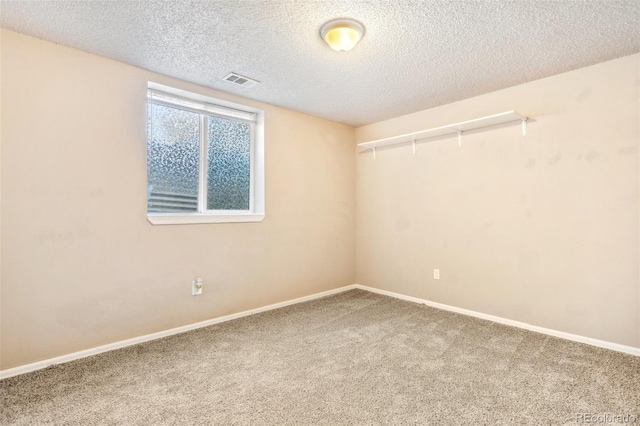 spare room with baseboards, carpet flooring, a textured ceiling, and visible vents