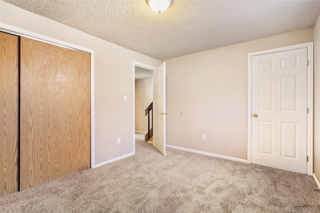 unfurnished bedroom with baseboards, carpet flooring, a textured ceiling, and a closet