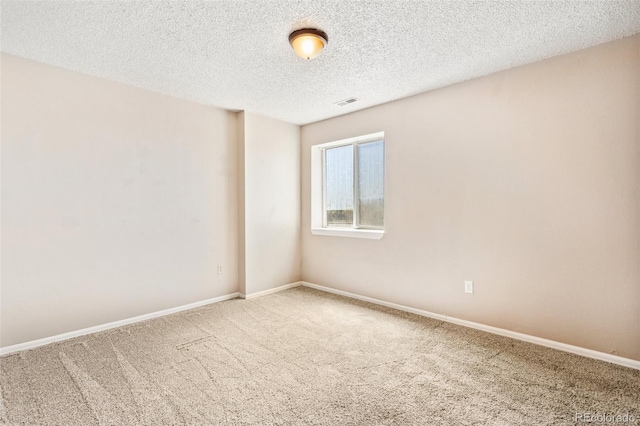 unfurnished room featuring baseboards, carpet flooring, a textured ceiling, and visible vents