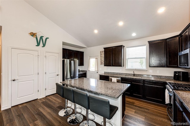 kitchen featuring a kitchen island, appliances with stainless steel finishes, sink, dark stone countertops, and dark wood-type flooring