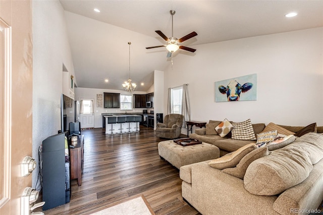 living room with high vaulted ceiling, ceiling fan with notable chandelier, and dark hardwood / wood-style flooring