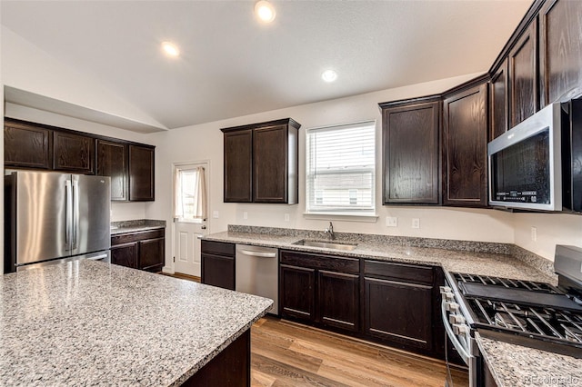 56459 E 23rd Pl, Strasburg, CO 80136 - kitchen with appliances with stainless steel finishes, healthy amount of natural light, lofted ceiling, dark brown cabinetry, and light wood-style floors