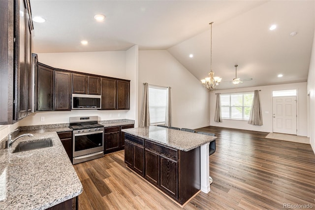 56459 E 23rd Pl, Strasburg, CO 80136 - kitchen with appliances with stainless steel finishes, a chandelier, dark brown cabinets, open floor plan, and a kitchen island