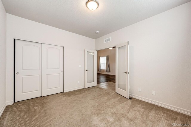 56459 E 23rd Pl, Strasburg, CO 80136 - unfurnished bedroom with light carpet, a closet, and french doors