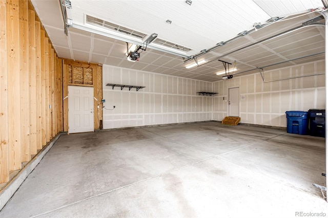 56459 E 23rd Pl, Strasburg, CO 80136 - garage featuring a garage door opener and wood walls