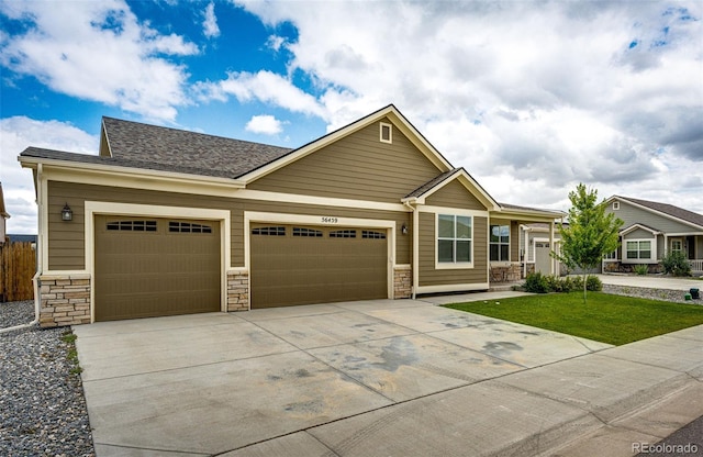 56459 E 23rd Pl, Strasburg, CO 80136 - craftsman-style house featuring an attached garage, concrete driveway, stone siding, a front lawn, and a shingled roof