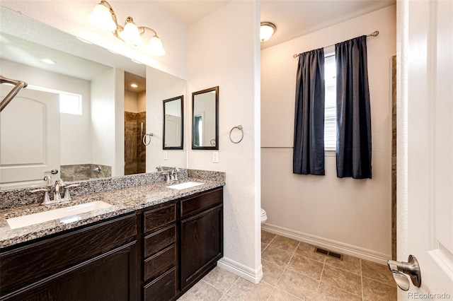 56459 E 23rd Pl, Strasburg, CO 80136 - bathroom featuring double vanity, a tile shower, and tile patterned flooring