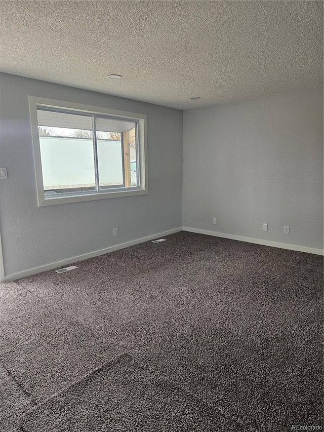 spare room with a textured ceiling and carpet floors