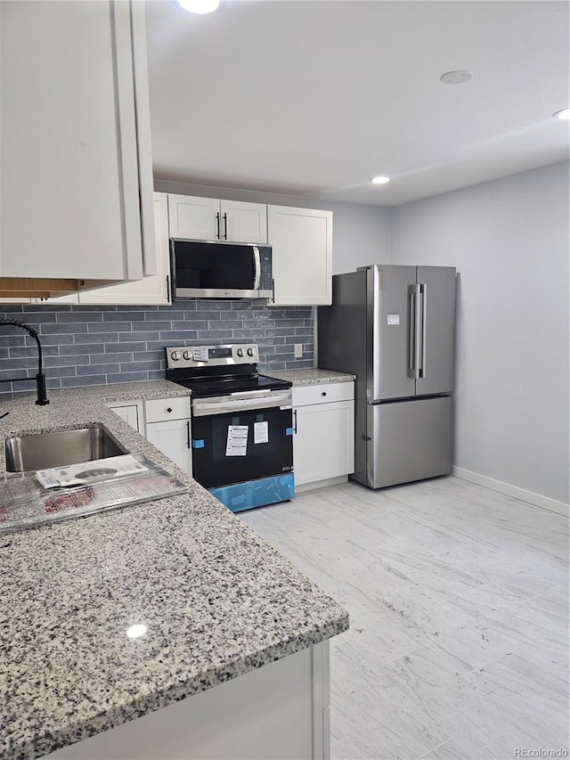 kitchen featuring white cabinetry, sink, stainless steel appliances, light stone counters, and backsplash