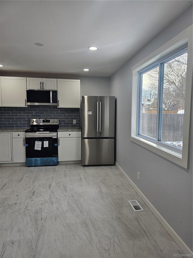 kitchen featuring decorative backsplash, light stone counters, white cabinetry, and stainless steel appliances