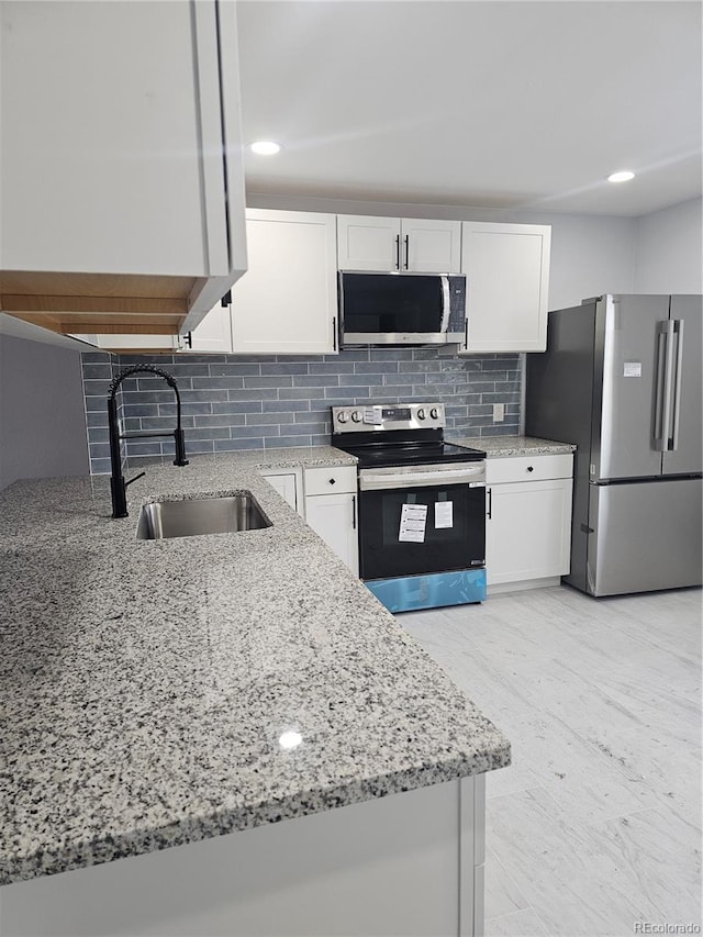 kitchen featuring white cabinets, sink, decorative backsplash, light stone countertops, and stainless steel appliances